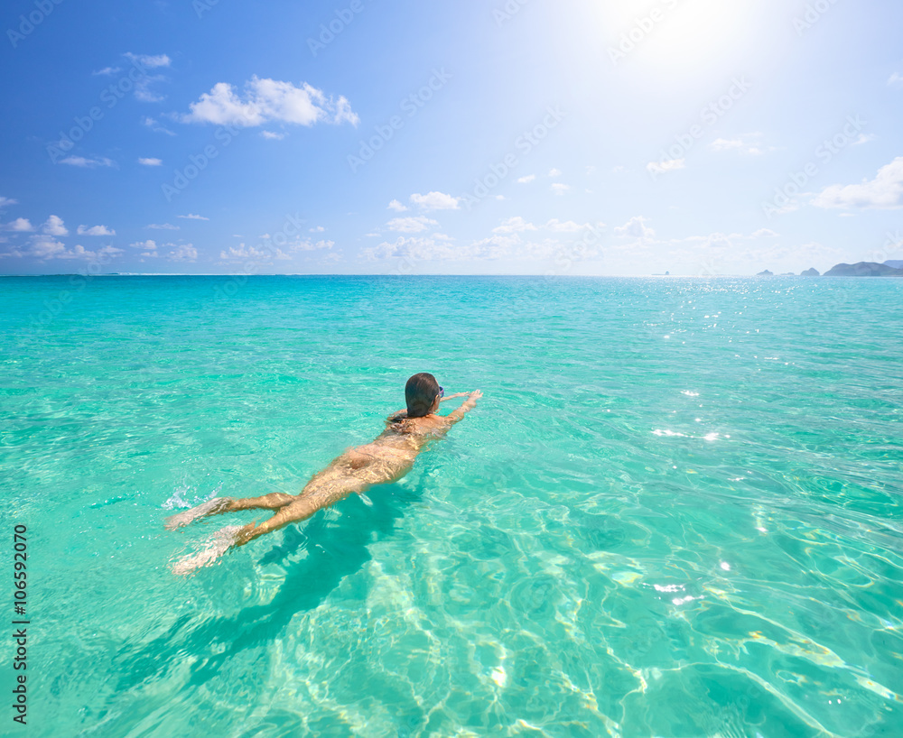 Young woman swimming in transparent tropical sea.