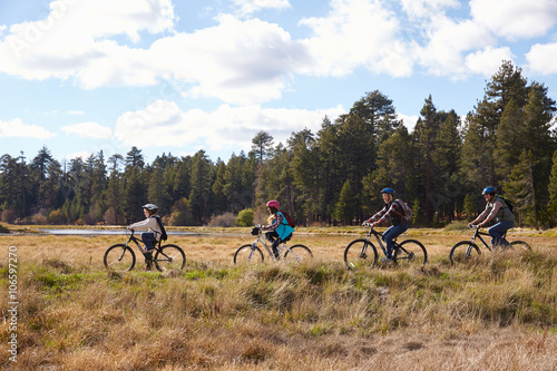 Family mountain biking in countryside, California