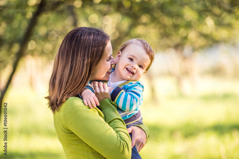 Mother holding little son in her arms, sunny nature Mother holding little son in her arms, sunny nature