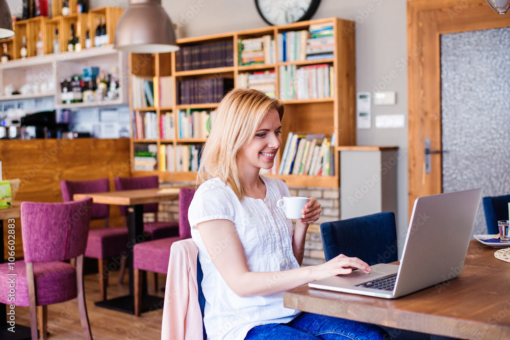 Blond woman with notebook in cafe drinking coffee Blond woman with notebook in cafe drinking coffee
