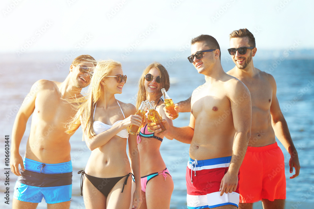 Happy young friends drinking beer at the beach, outdoors Happy young friends drinking beer at the beach, outdoors