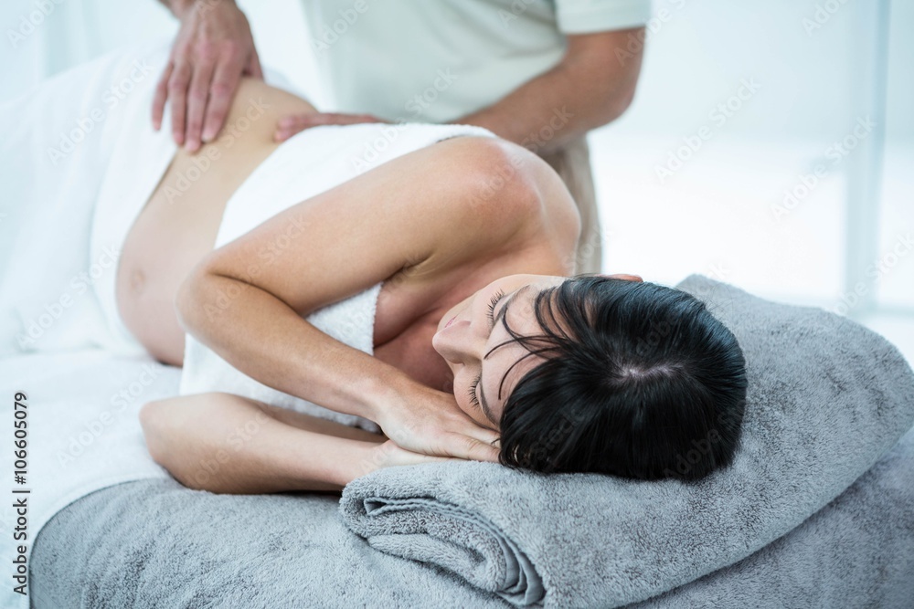 Pregnant woman receiving a back massage from masseur - obrazy, fototapety, plakaty 