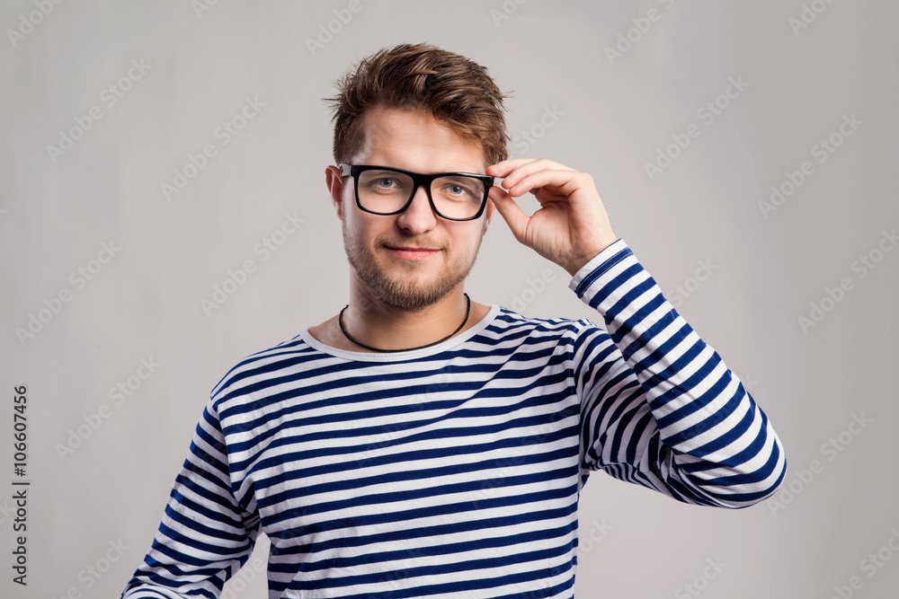 Man in striped t-shirt and eyeglasses against gray background. Man in striped t-shirt and eyeglasses against gray background.