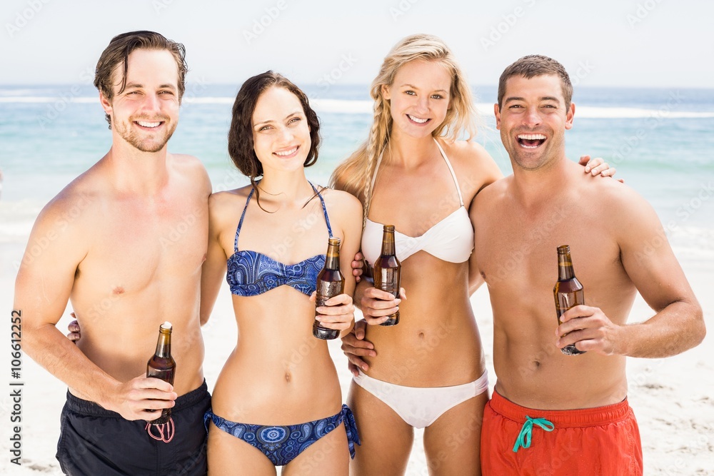 Happy friends on the beach with beer bottles