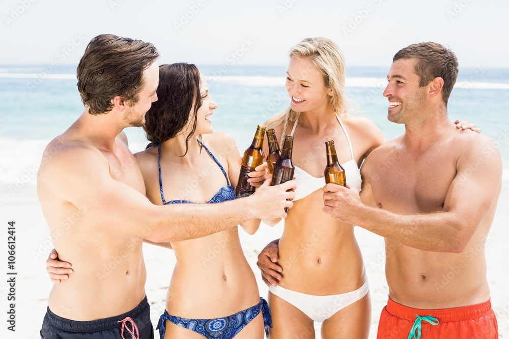 Happy friends toasting beer bottles on the beach Happy friends toasting beer bottles on the beach