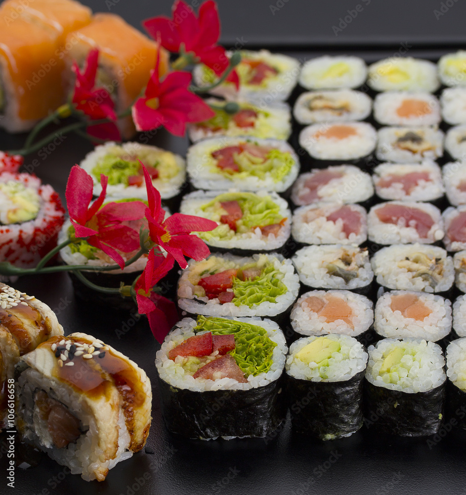 Sushi set on a black plate over dark background Sushi set on a black plate over dark background