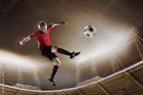 Athlete kicking soccer ball in stadium