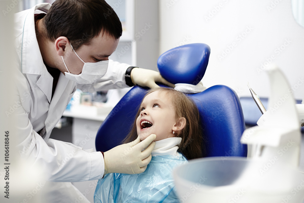 Caucasian dentist examining girl's teeth