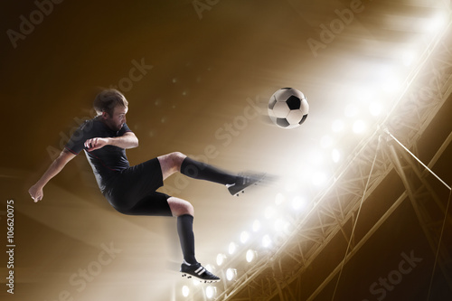 Athlete kicking soccer ball in stadium