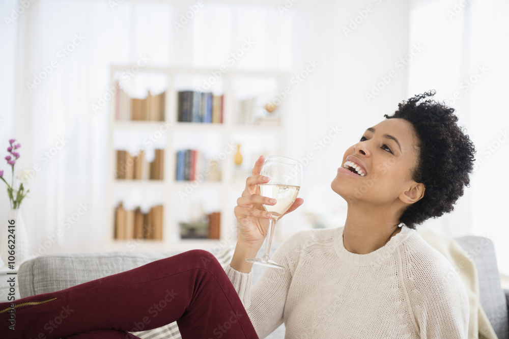 Black woman drinking wine on sofa