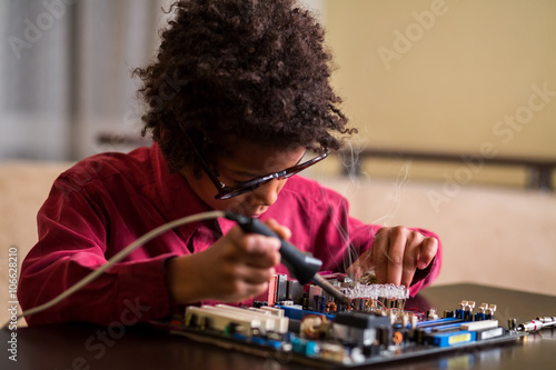 Afro boy soldering motherboard.