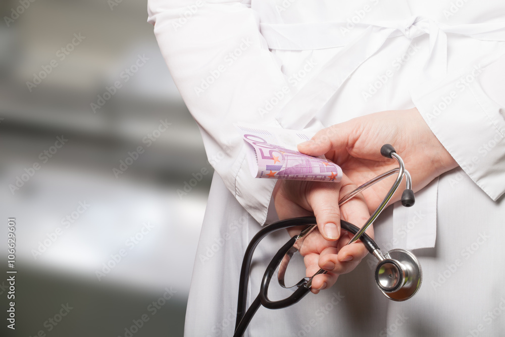 The doctor put his hands with stethoscope and money behind his b