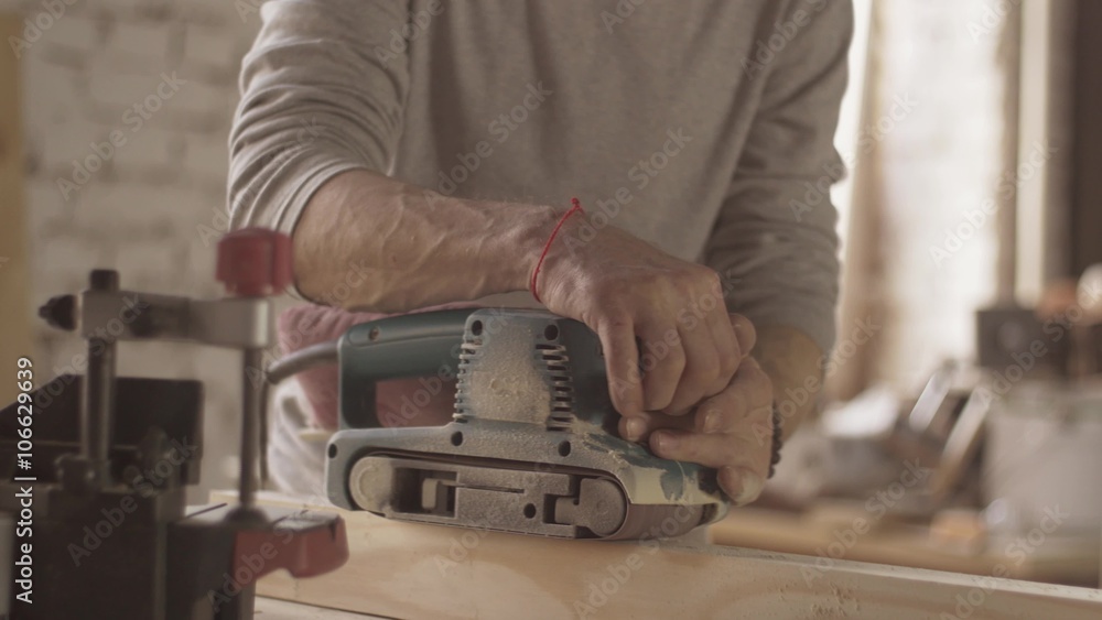 Joiner treat surface of wooden board by belt sander. Furniture. Close up. Move forward and backward, pressing Joiner treat surface of wooden board by belt sander. Furniture. Close up. Move forward and backward, pressing