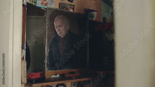Elder pensive at the mirror wearing sweater photo