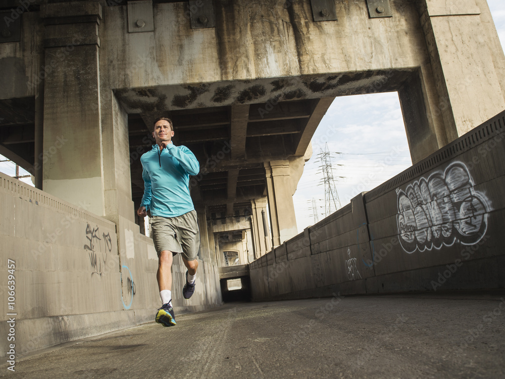 Caucasian man running in urban tunnel Caucasian man running in urban tunnel