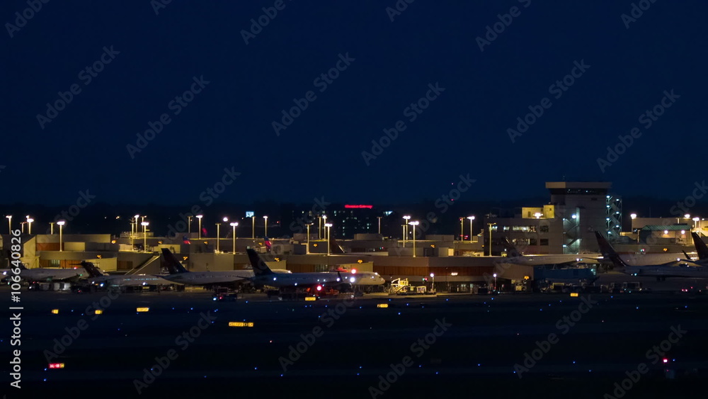 Atlanta International Airport ATL Exterior in the Evening with Passenger Jets Parked at Terminals and Taking Off from a Runway Atlanta International Airport ATL Exterior in the Evening with Passenger Jets Parked at Terminals and Taking Off from a Runway