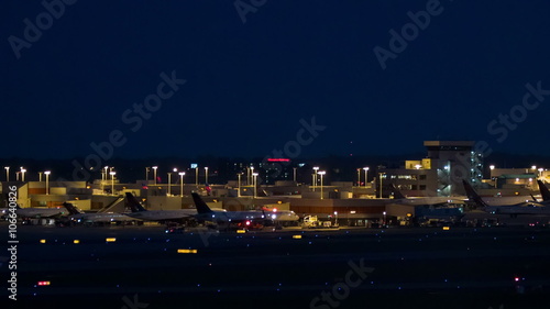 Atlanta International Airport ATL Exterior in the Evening with Passenger Jets Parked at Terminals and Taking Off from a Runway photo