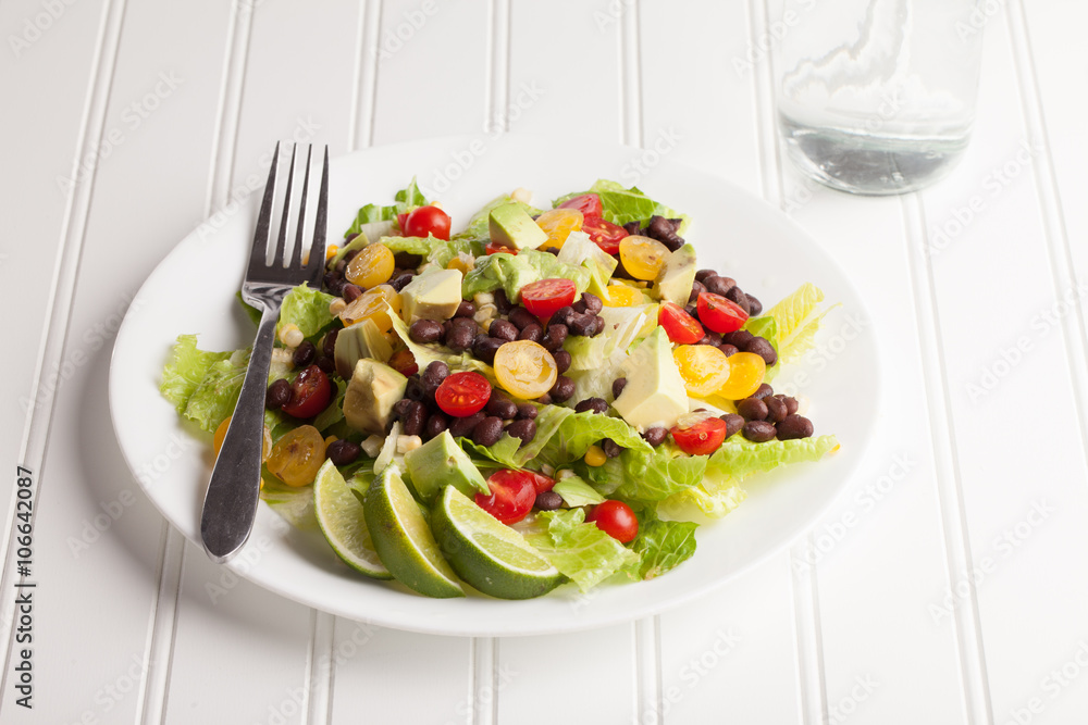Southwest black bean, lime, cilantro, tomato, and avocado salad on a vintage antique plate with water