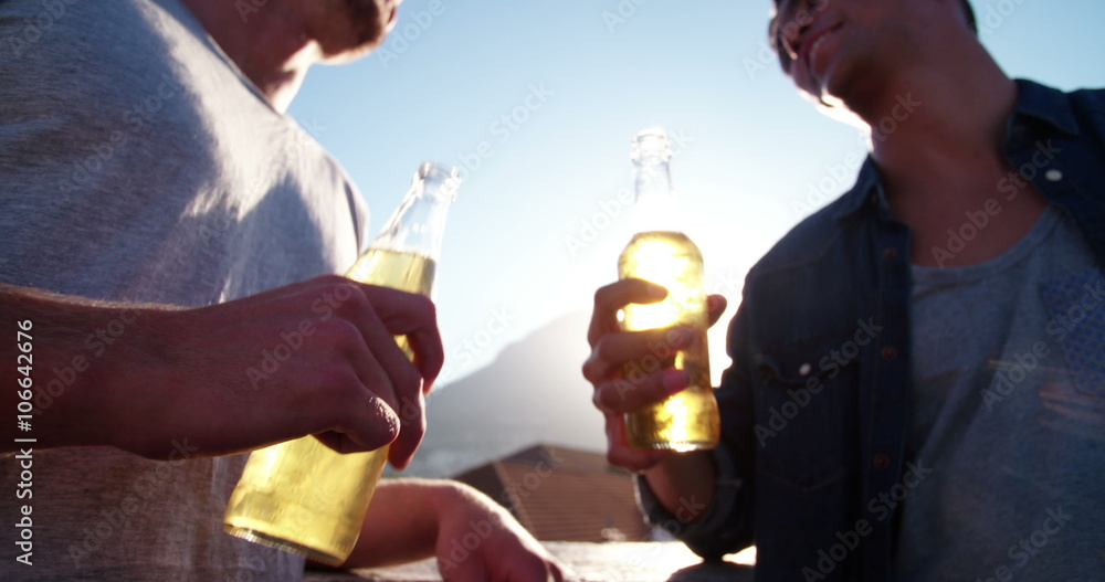 Two friends celebrating on rooftop and toasting with beer Two friends celebrating on rooftop and toasting with beer
