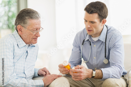 Caucasian doctor and patient discussing medication at home photo