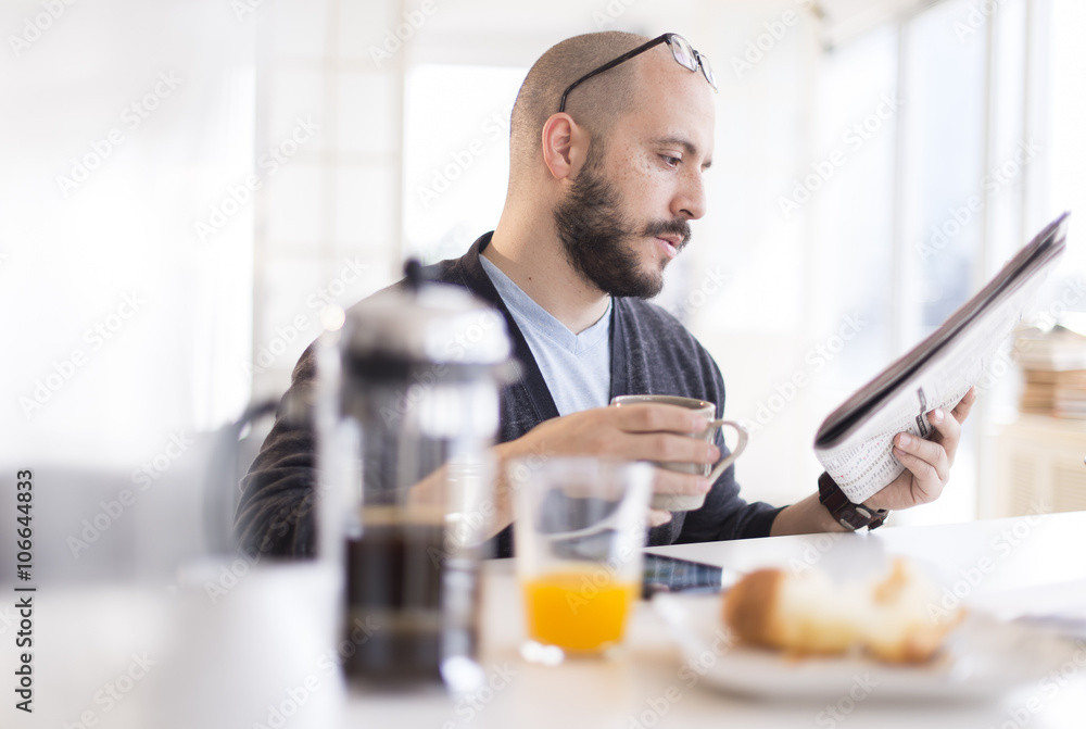 Hispanic man reading newspaper at breakfast Hispanic man reading newspaper at breakfast