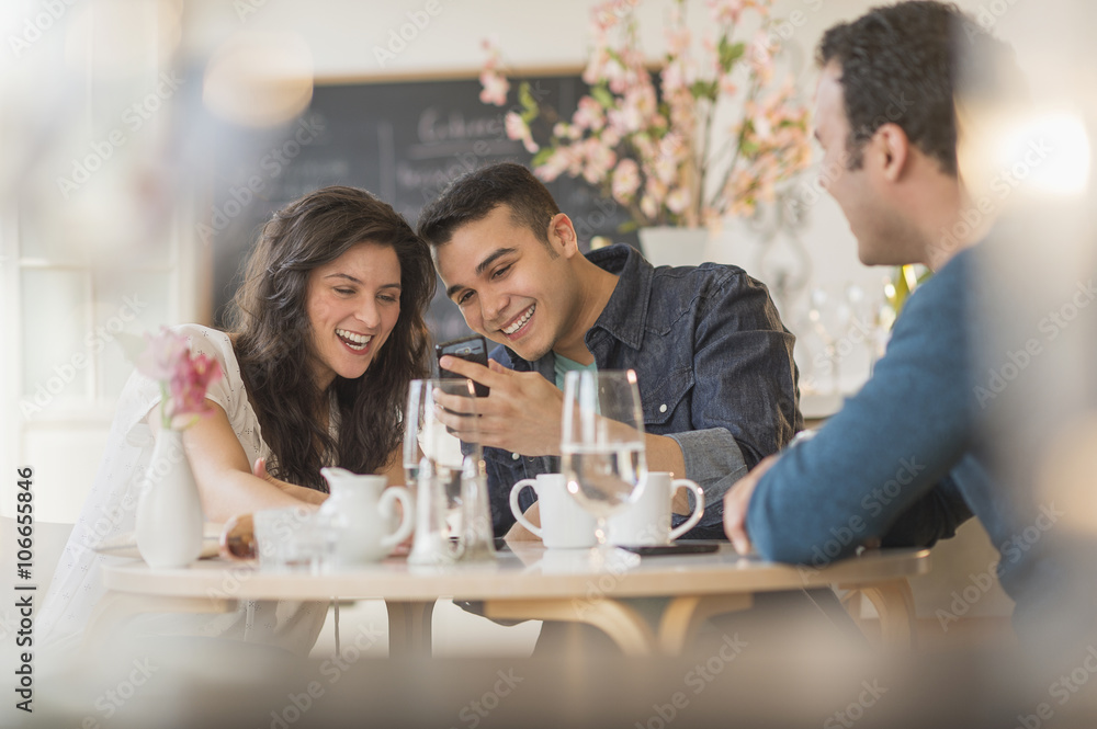 Hispanic friends using cell phone in cafe Hispanic friends using cell phone in cafe