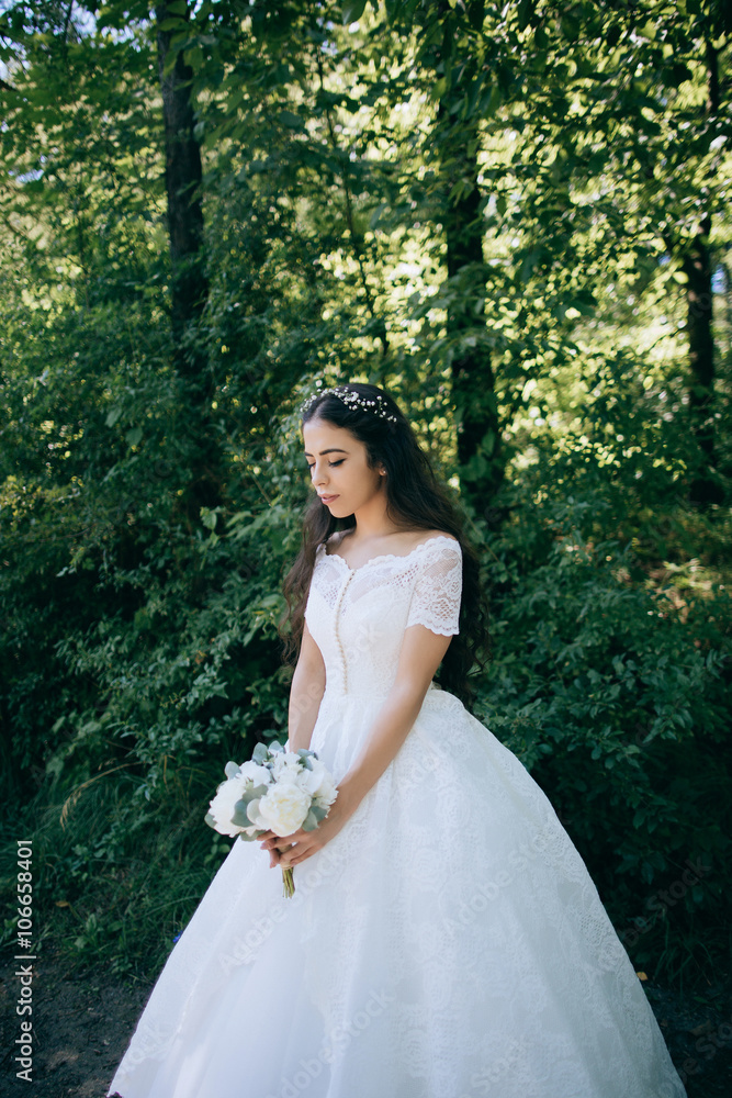Beautiful sensual bride with rustic wedding hairstyle in the forest. Outdoor portrait of young gorgeous bride. Wedding.