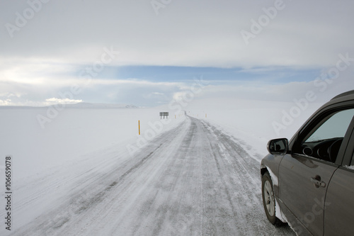 Car driving on rural road in snowy landscape photo