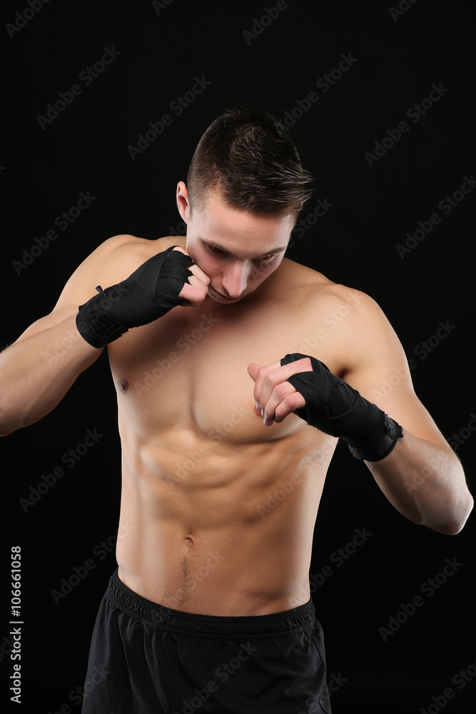 Young boxer training on dark background
