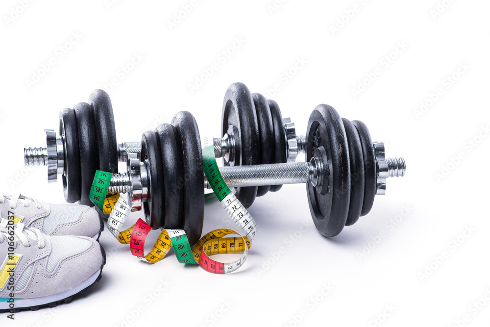 Dumbbells with measuring tape and sneakers on white Dumbbells with measuring tape and sneakers on white