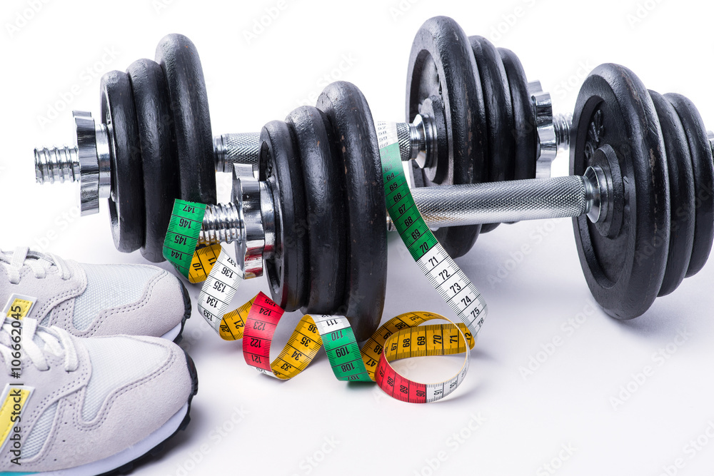 Dumbbells with measuring tape and sneakers on white Dumbbells with measuring tape and sneakers on white