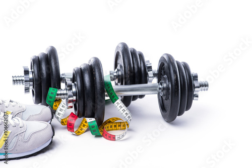 Dumbbells with measuring tape and sneakers on white