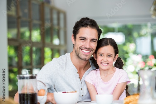 Portrait of smiling father and daughter at table 