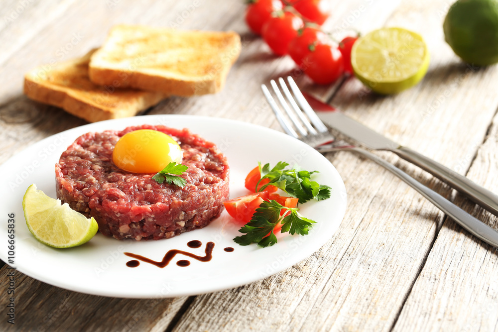 Beef tartare with egg yolk on a grey wooden table Beef tartare with egg yolk on a grey wooden table