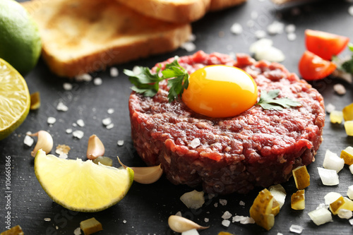 Beef tartare with egg yolk on a black wooden table