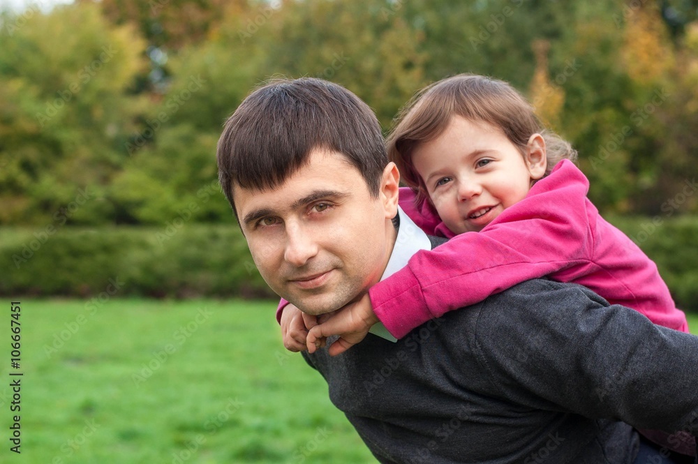 Daughter sitting at daddy on the back and smiling Daughter sitting at daddy on the back and smiling