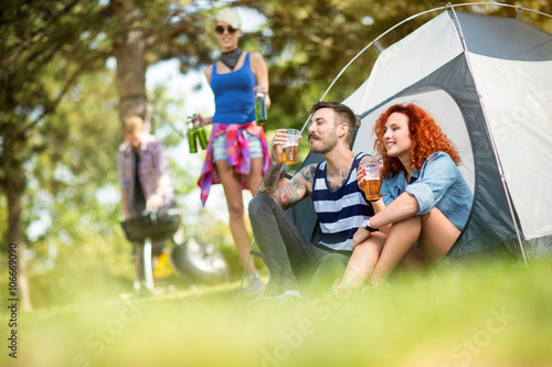 Man and woman drinks beer in front of tent at camping © luckybusiness