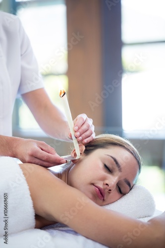 Woman receiving ear candle treatment