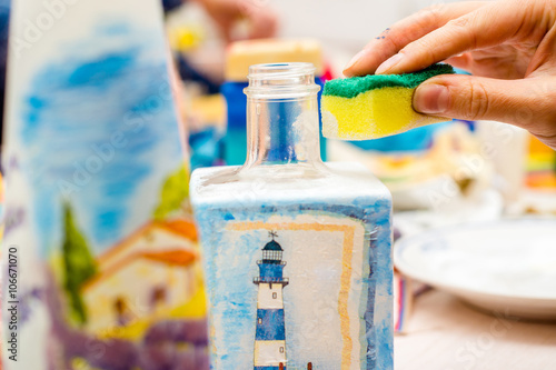 decoupage bottle. Professional painter paints a souvenir