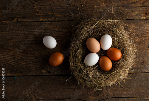 Fresh chicken eggs in a nest on a wooden background