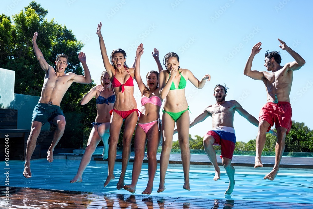 Obraz premium Happy friends jumping in swimming pool
