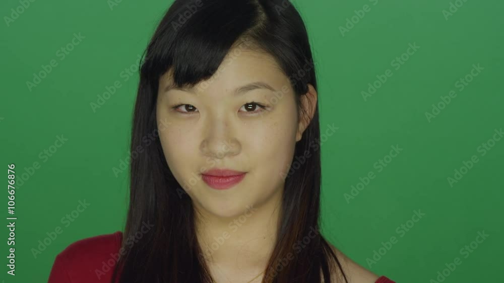 Young Asian woman smiling pleasantly, on a green screen studio background Young Asian woman smiling pleasantly, on a green screen studio background