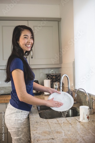 Foto Portrait of happy woman washing up in the kitchen