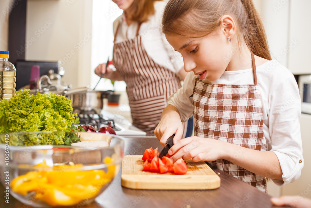 Small teenage girl cutting tomatoes in salad Small teenage girl cutting tomatoes in salad