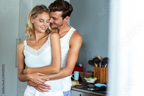 Romantic man embracing woman from behind at home