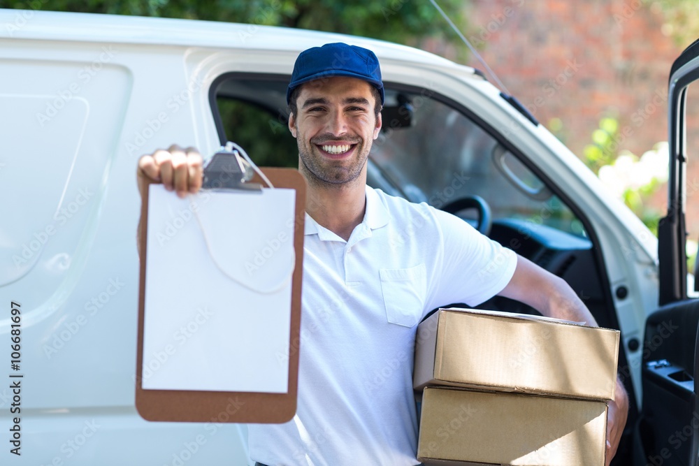 Smiling delivery man showing clipboard Smiling delivery man showing clipboard