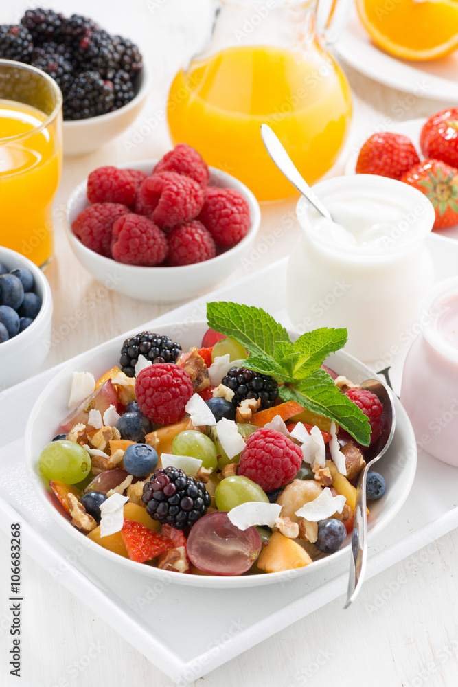 fruit salad in a bowl and various yoghurt, vertical, top view fruit salad in a bowl and various yoghurt, vertical, top view