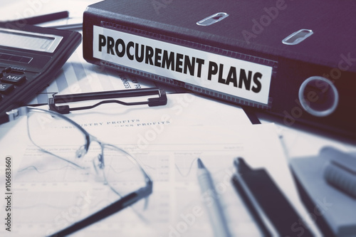 Ring Binder with inscription Procurement Plans on Background of Working Table with Office Supplies, Glasses, Reports. Toned Illustration. Business Concept on Blurred Background.