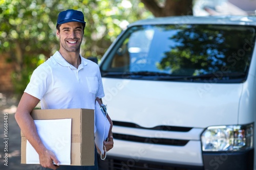 Obraz na plátně Portrait of smiling delivery person with cardboard box