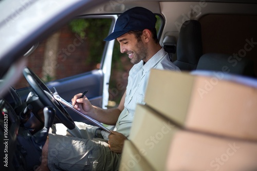 Fotografija Smiling delivery man writing in clipboard